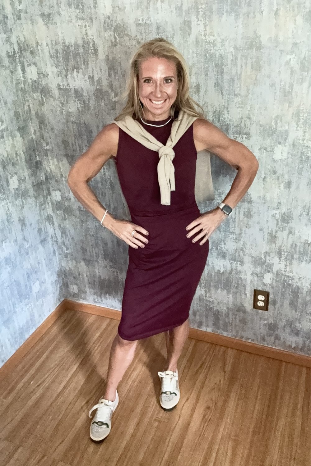 A wine knit dress with a cream sweater tied over the shoulders