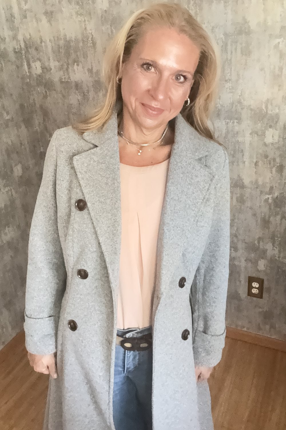 Heather in a light grey double-breasted wool coat, open over a blush top and jeans